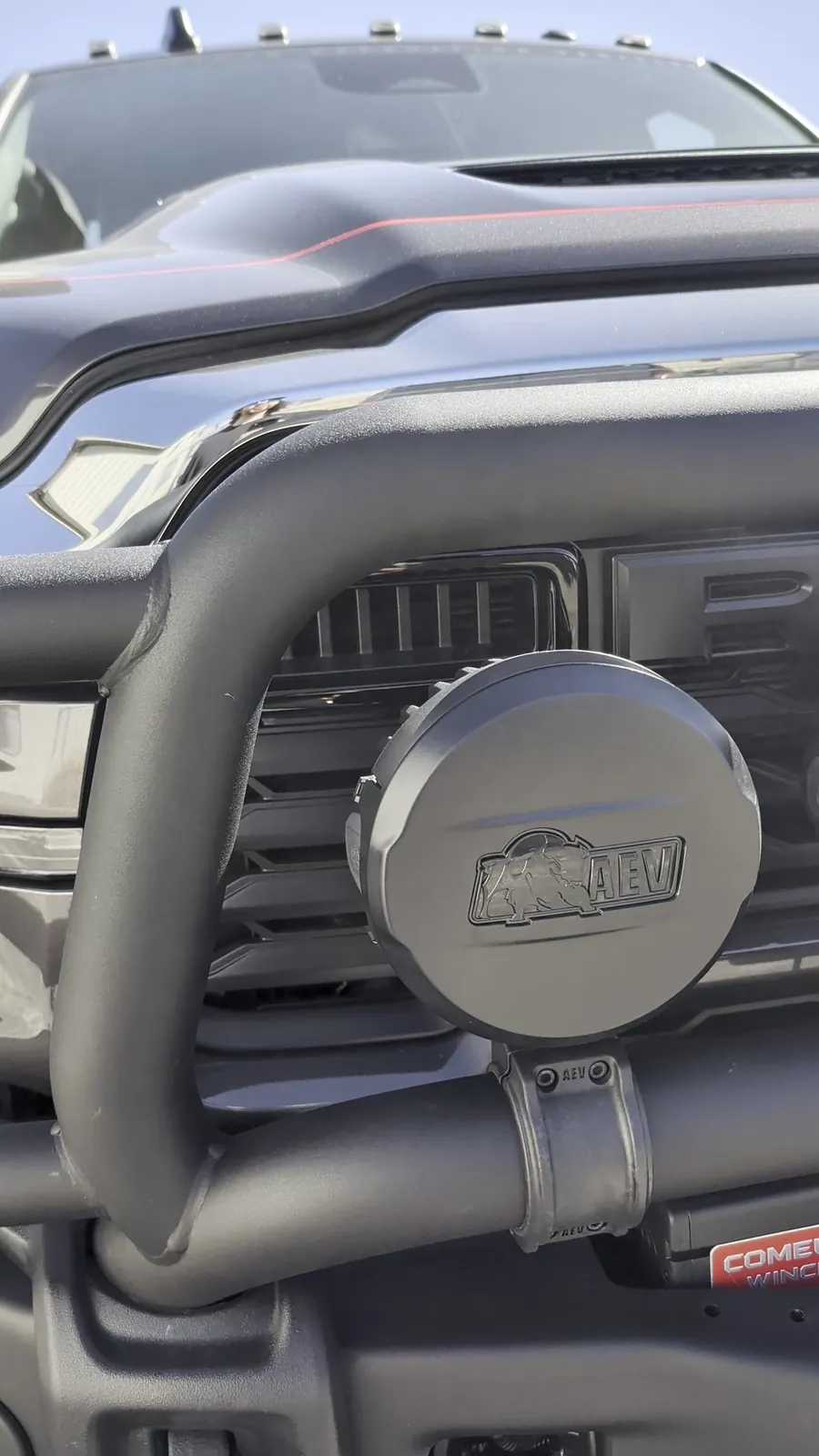 Close-up of an AEV 7000-series light on the brush guard and the Come Up winch